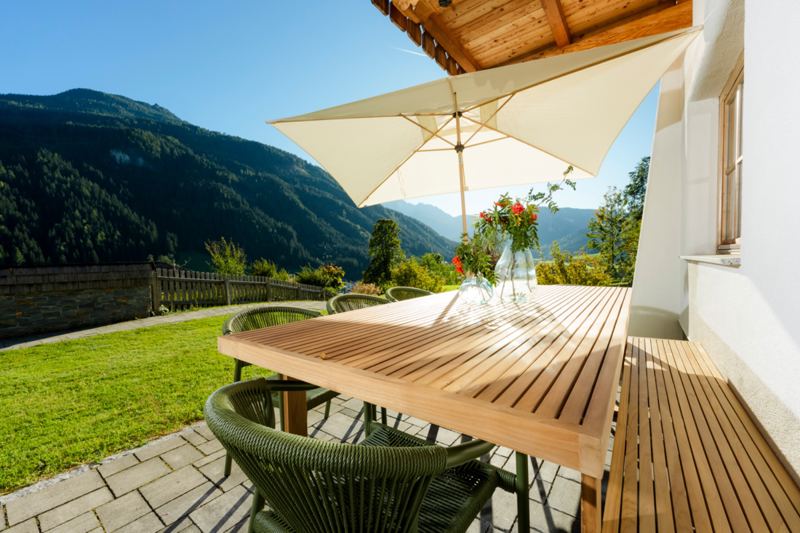 Bergblick von der Terrasse mit Gartenmöbel und Sonnenschirm